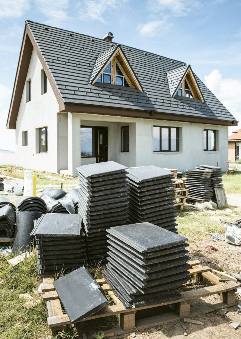 Matériaux de toiture empilés devant une maison en construction.